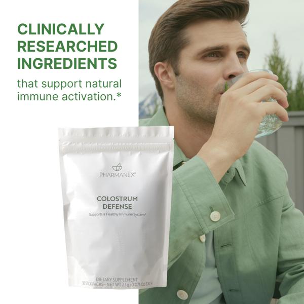 Man drinking water with a Pharmanex Colostrum Defense package in the foreground, highlighting clinically researched ingredients for immune support.