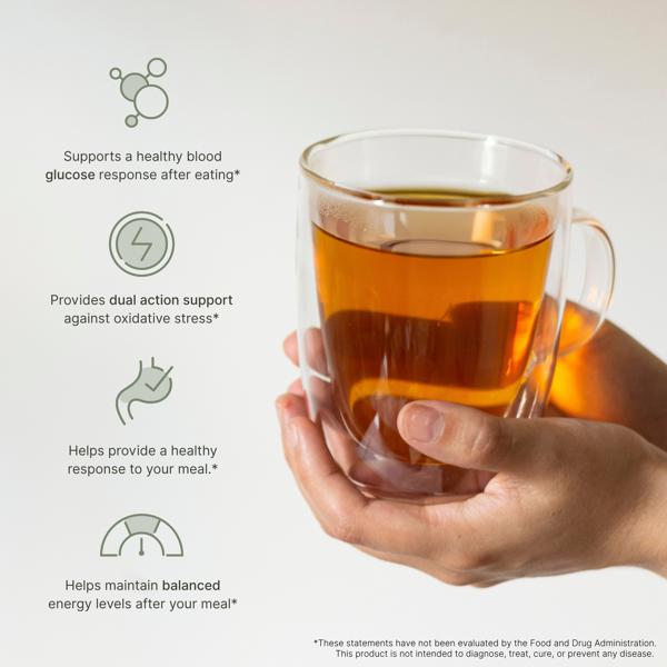 Glass mug of tea held by a hand with M Smart health benefits text on a light gray background