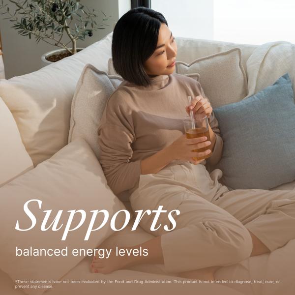 Woman sitting on a couch holding a drink with text about balanced energy while taking m-smart